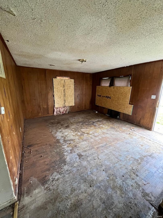 unfurnished room featuring wood walls and a textured ceiling