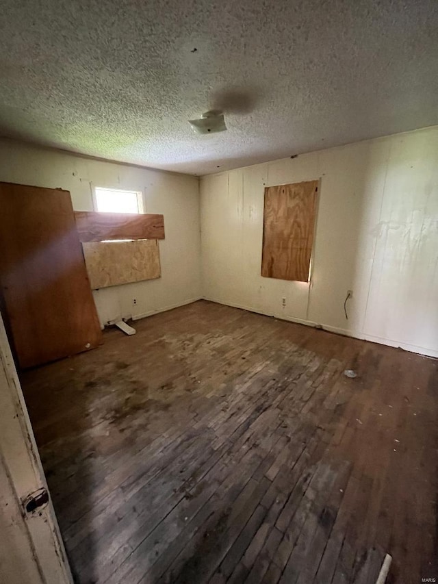 unfurnished room featuring dark wood-type flooring and a textured ceiling