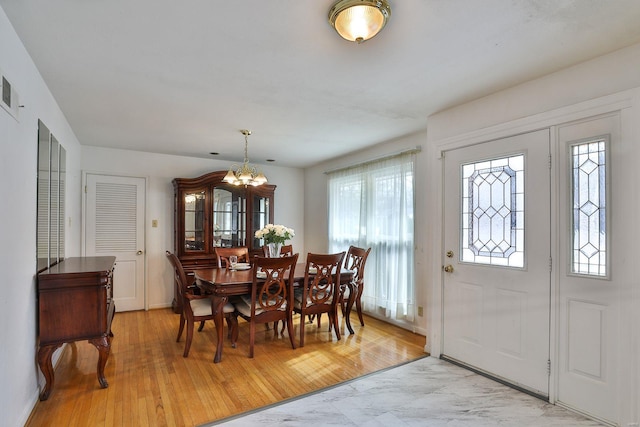 dining space featuring light hardwood / wood-style floors and a chandelier