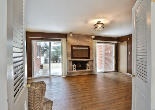 unfurnished living room with a fireplace, wood walls, and hardwood / wood-style flooring