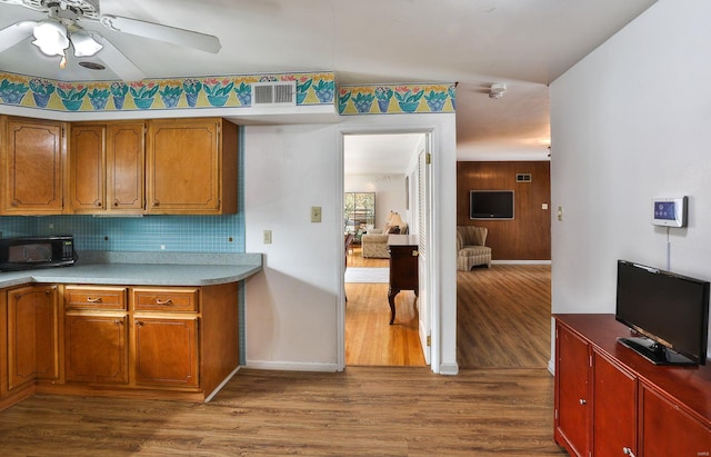 kitchen featuring hardwood / wood-style flooring, ceiling fan, and backsplash