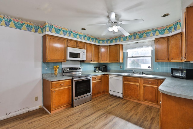 kitchen with white appliances, sink, light wood-type flooring, ceiling fan, and decorative backsplash