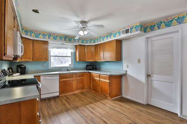 kitchen featuring light hardwood / wood-style flooring, sink, backsplash, white appliances, and ceiling fan