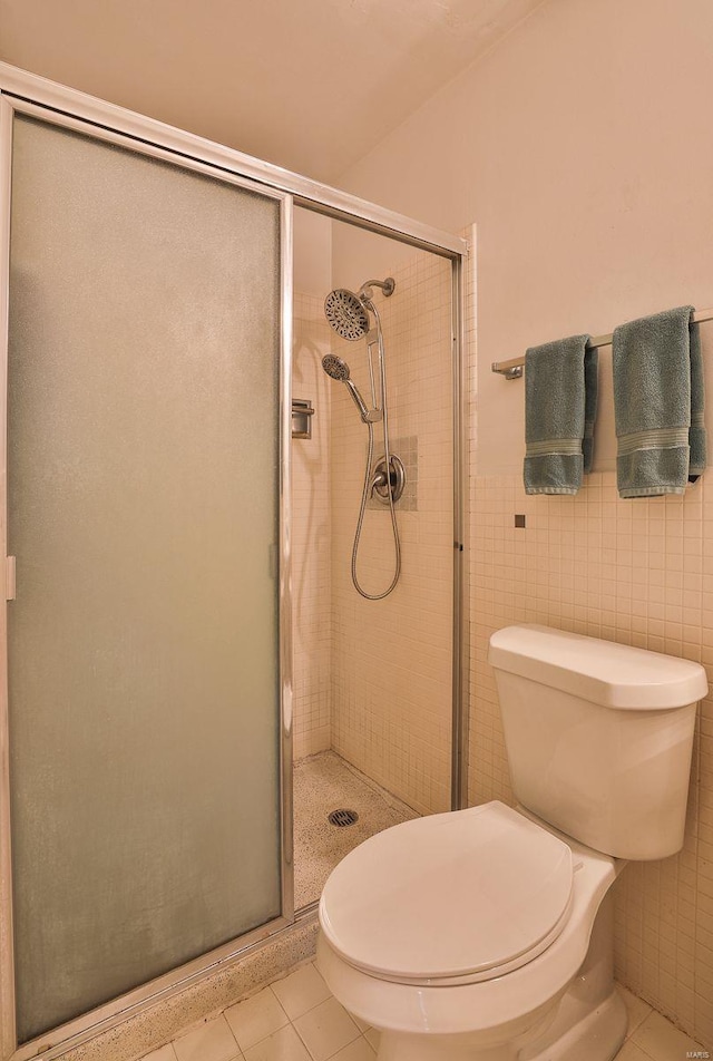 bathroom with tile patterned floors, tile walls, toilet, and walk in shower