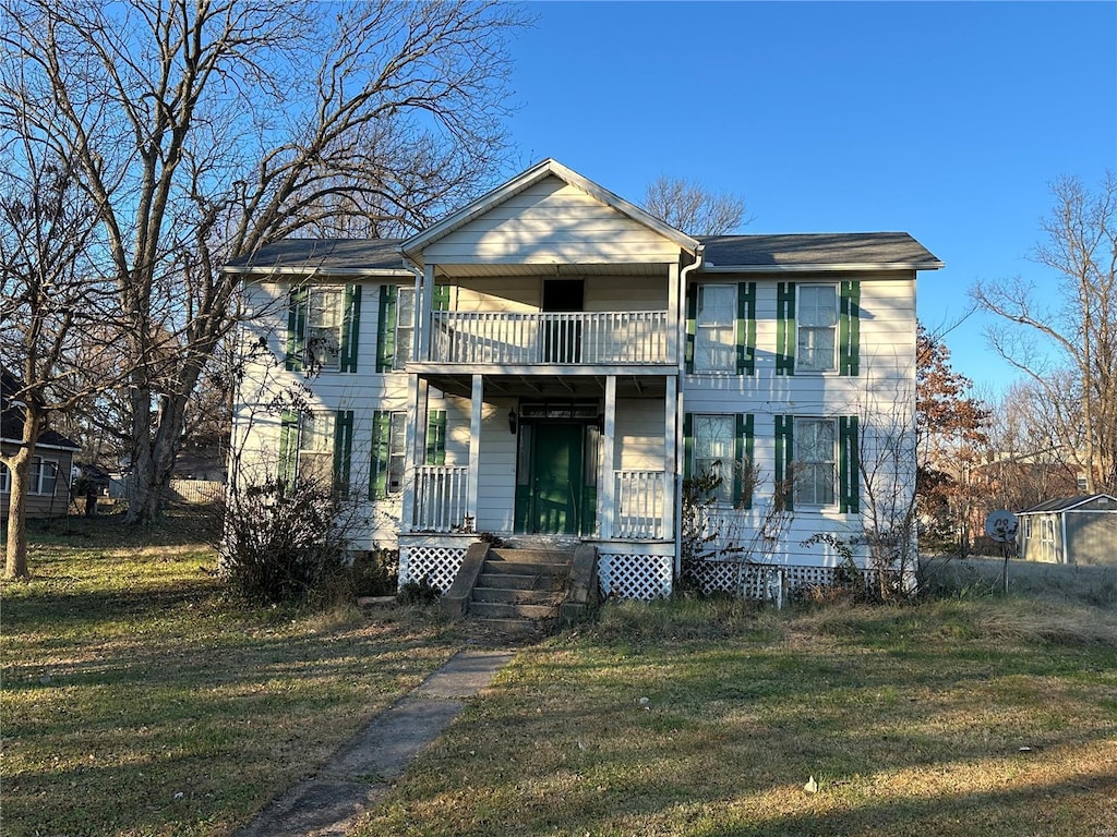 view of front of home with a balcony and a front yard