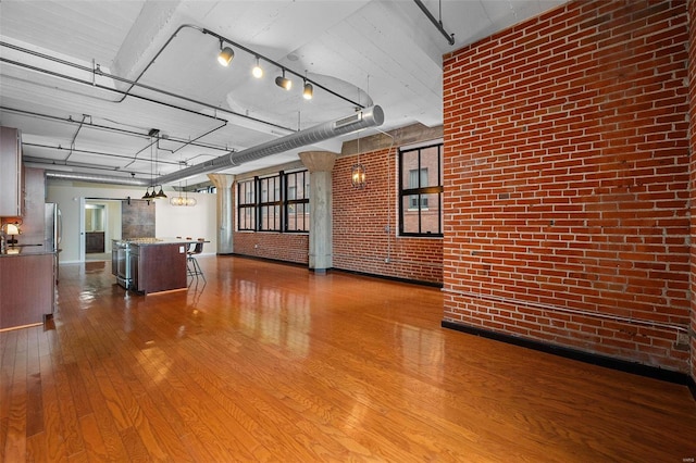 interior space with wood-type flooring, rail lighting, and brick wall