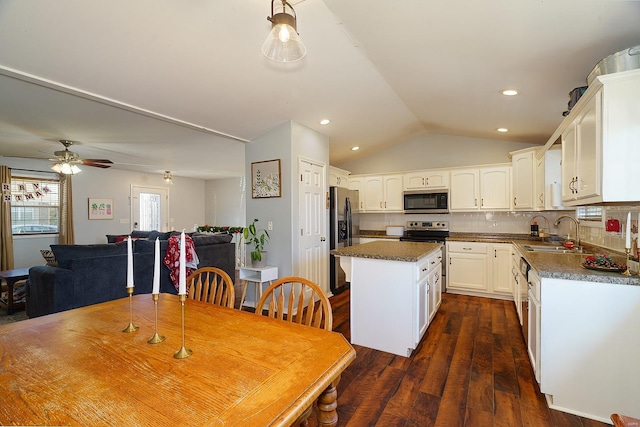 kitchen featuring sink, stainless steel appliances, dark hardwood / wood-style floors, lofted ceiling, and a kitchen island