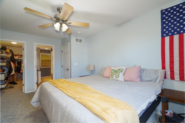 carpeted bedroom featuring ceiling fan, a closet, and a spacious closet