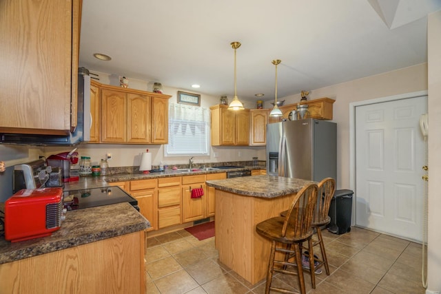 kitchen featuring sink, light tile patterned flooring, stainless steel refrigerator with ice dispenser, a breakfast bar area, and a kitchen island