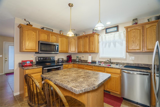 kitchen with pendant lighting, a center island, dark tile patterned flooring, sink, and stainless steel appliances