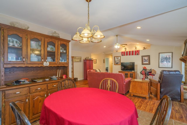 dining space with light wood-type flooring, ceiling fan with notable chandelier, and lofted ceiling