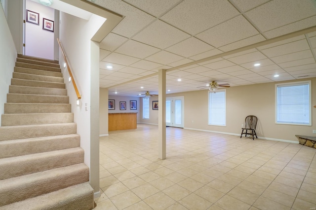 basement featuring a paneled ceiling, ceiling fan, and light tile patterned floors