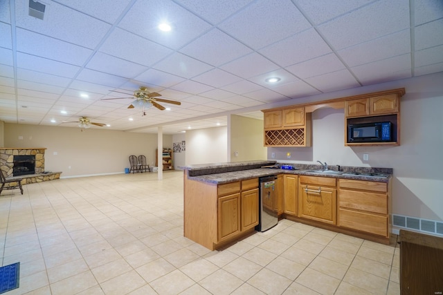 kitchen with stainless steel dishwasher, black microwave, ceiling fan, sink, and a stone fireplace