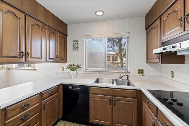 kitchen with light countertops, a sink, black appliances, and wallpapered walls