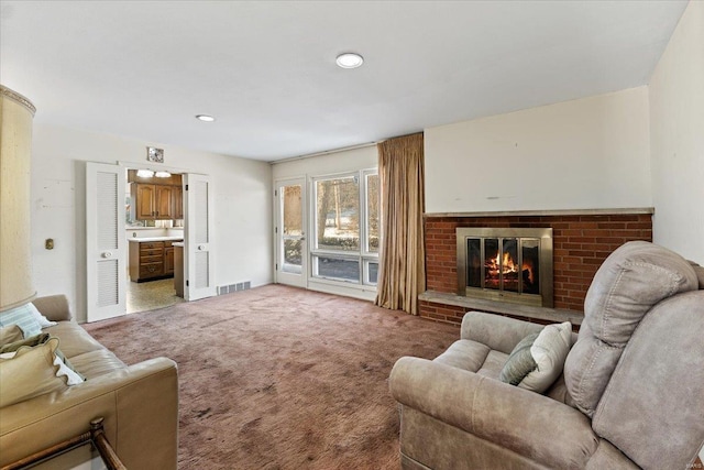 living room with carpet, visible vents, and a brick fireplace