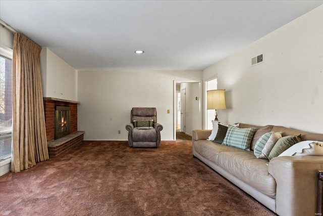 living room featuring a brick fireplace, visible vents, and carpet flooring