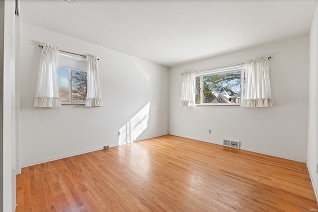 spare room featuring light wood-type flooring, baseboards, and visible vents