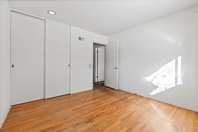 unfurnished bedroom with a closet, light wood-type flooring, and visible vents