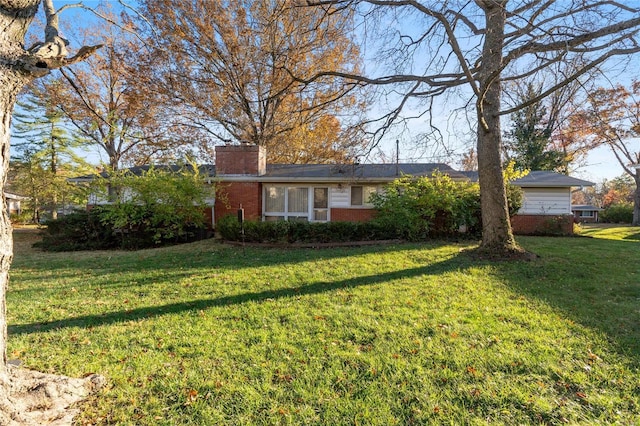 view of front of home with brick siding, a chimney, and a front lawn