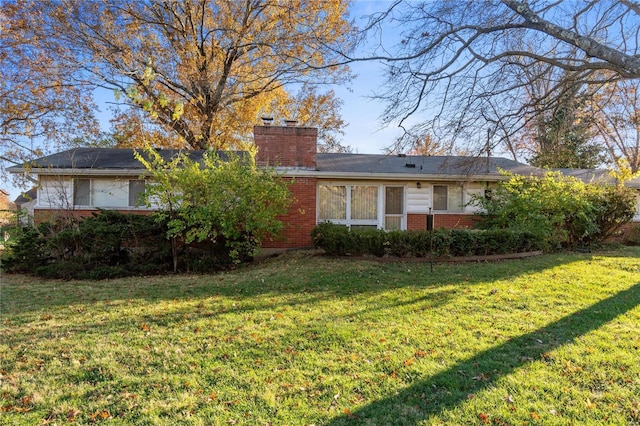 view of front of home with brick siding, a chimney, and a front yard