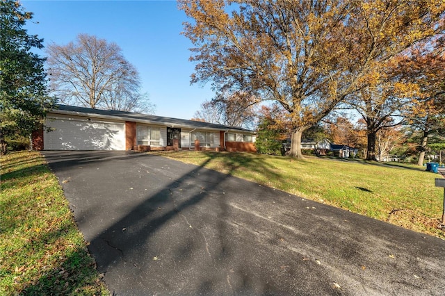 ranch-style house featuring aphalt driveway, a front yard, brick siding, and an attached garage