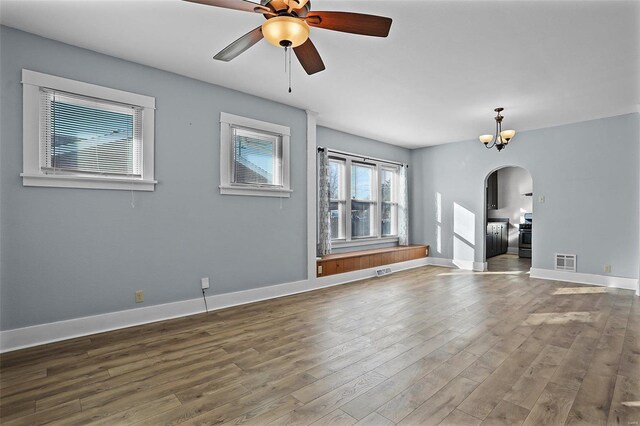 spare room featuring ceiling fan with notable chandelier and wood-type flooring