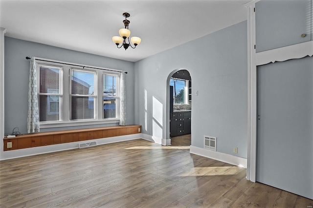 unfurnished room with hardwood / wood-style floors and a notable chandelier