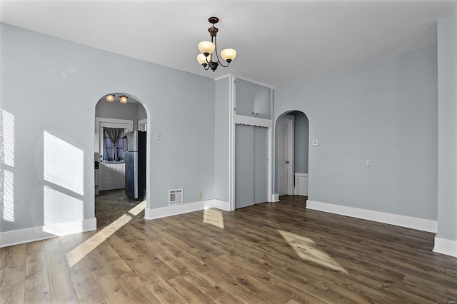 spare room featuring dark hardwood / wood-style floors and a notable chandelier