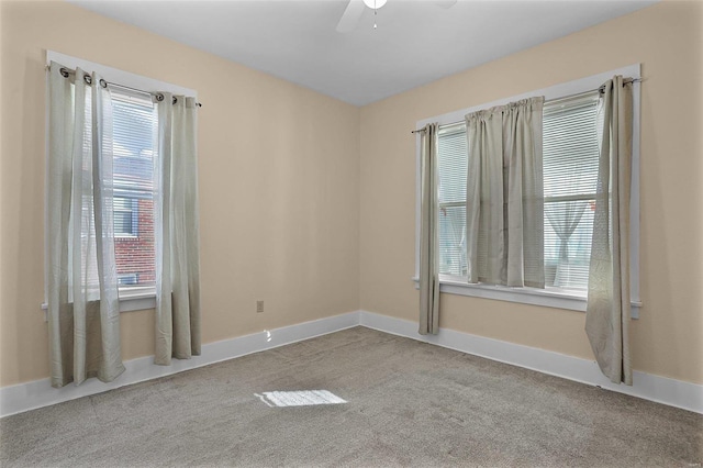 empty room with ceiling fan, light colored carpet, and a wealth of natural light