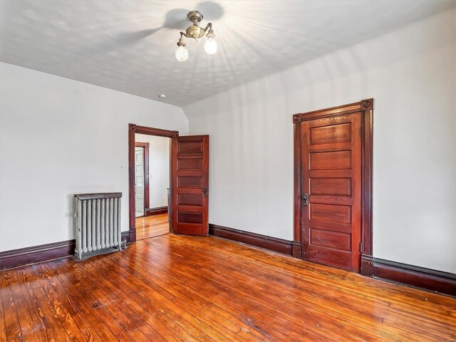 unfurnished room with wood-type flooring and radiator heating unit