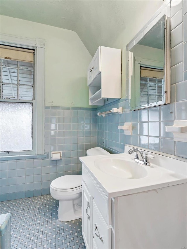 bathroom featuring tile patterned flooring, vanity, tile walls, and toilet