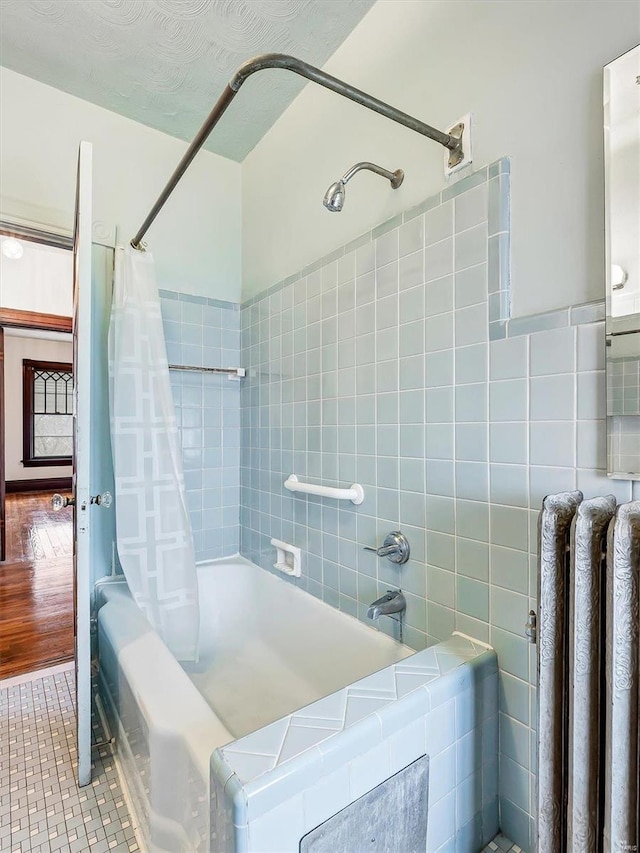 bathroom with shower / bathtub combination with curtain, wood-type flooring, tile walls, and radiator