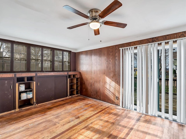 unfurnished room featuring hardwood / wood-style flooring, ceiling fan, and wood walls