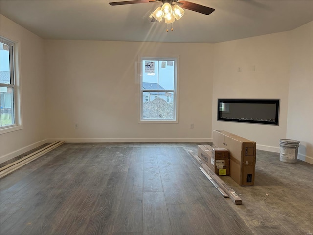 unfurnished living room featuring dark wood-type flooring and ceiling fan