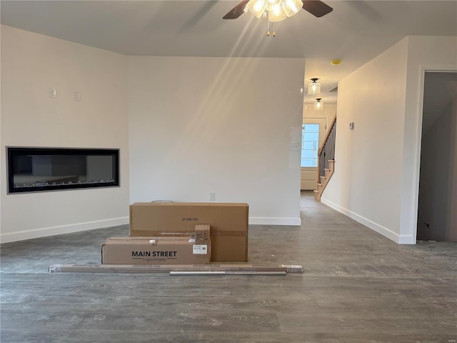 unfurnished living room featuring dark hardwood / wood-style flooring and ceiling fan