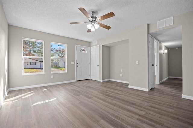 unfurnished room with a textured ceiling, ceiling fan, and dark wood-type flooring