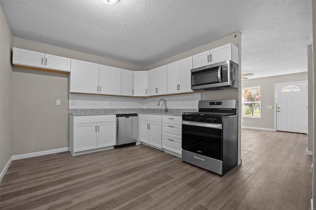 kitchen featuring stainless steel appliances, white cabinetry, and dark hardwood / wood-style floors