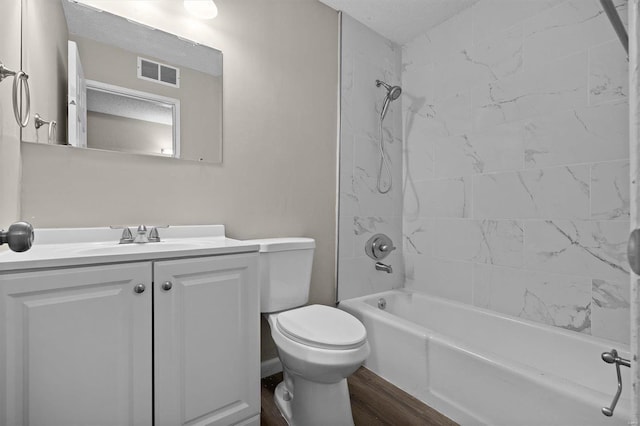 full bathroom with vanity, a textured ceiling, tiled shower / bath combo, hardwood / wood-style flooring, and toilet