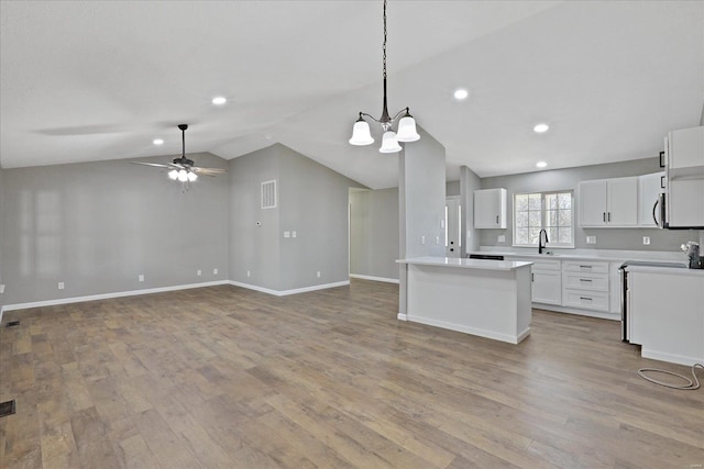 kitchen with ceiling fan with notable chandelier, white cabinetry, vaulted ceiling, and light hardwood / wood-style floors