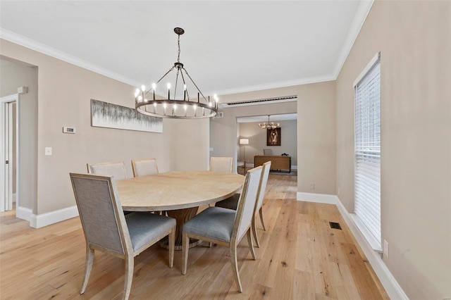 dining room with light wood-type flooring, an inviting chandelier, and ornamental molding