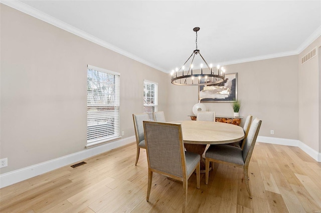 dining space featuring crown molding, light hardwood / wood-style flooring, and a chandelier