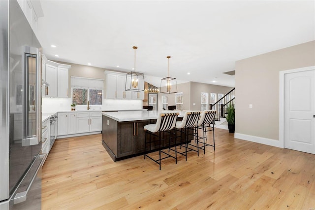 kitchen with high end fridge, a kitchen island, decorative light fixtures, white cabinetry, and a breakfast bar area