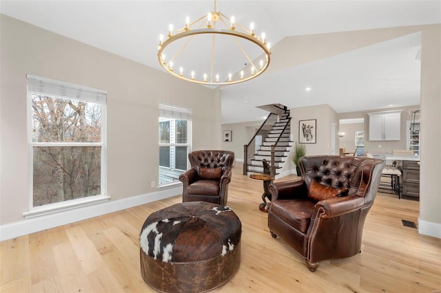 living area featuring light hardwood / wood-style flooring, vaulted ceiling, and a notable chandelier