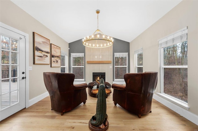 sitting room featuring a large fireplace, a notable chandelier, light hardwood / wood-style floors, and lofted ceiling