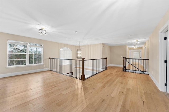 spare room with light hardwood / wood-style floors and a chandelier