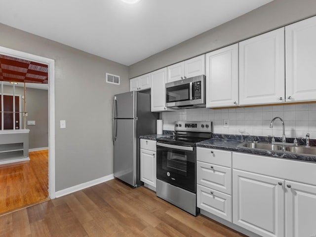 kitchen with appliances with stainless steel finishes, white cabinetry, light hardwood / wood-style flooring, and sink