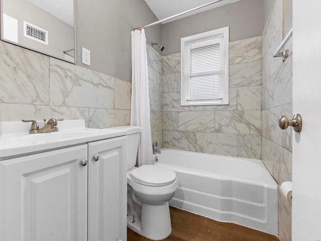 full bathroom featuring hardwood / wood-style floors, vanity, toilet, tile walls, and shower / tub combo