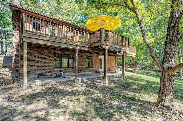 rear view of property featuring a wooden deck and a patio