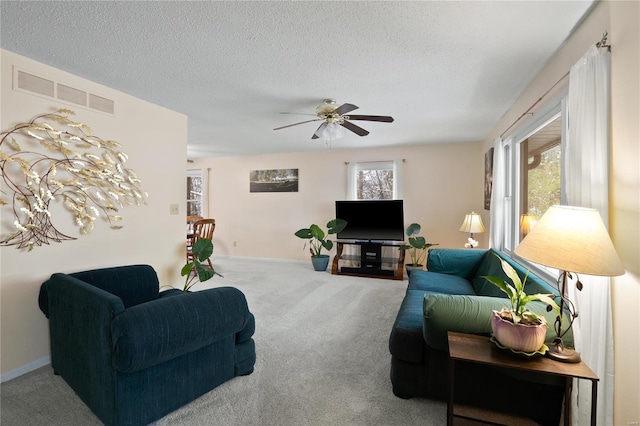 carpeted living room with ceiling fan and a textured ceiling