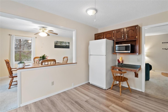 kitchen featuring dark brown cabinets, a textured ceiling, ceiling fan, white refrigerator, and light hardwood / wood-style floors